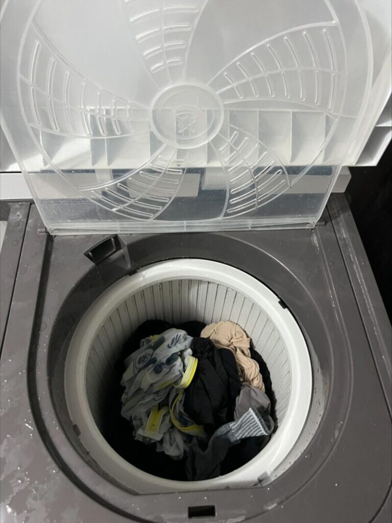 ドミニカ共和国の洗濯において、脱水槽に洗濯物を入れている写真です。
